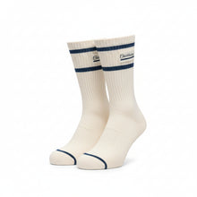 A pair of off-white crew socks with two dark blue stripes near the cuff, featuring a small embroidered logo that reads 'Buckingham'.